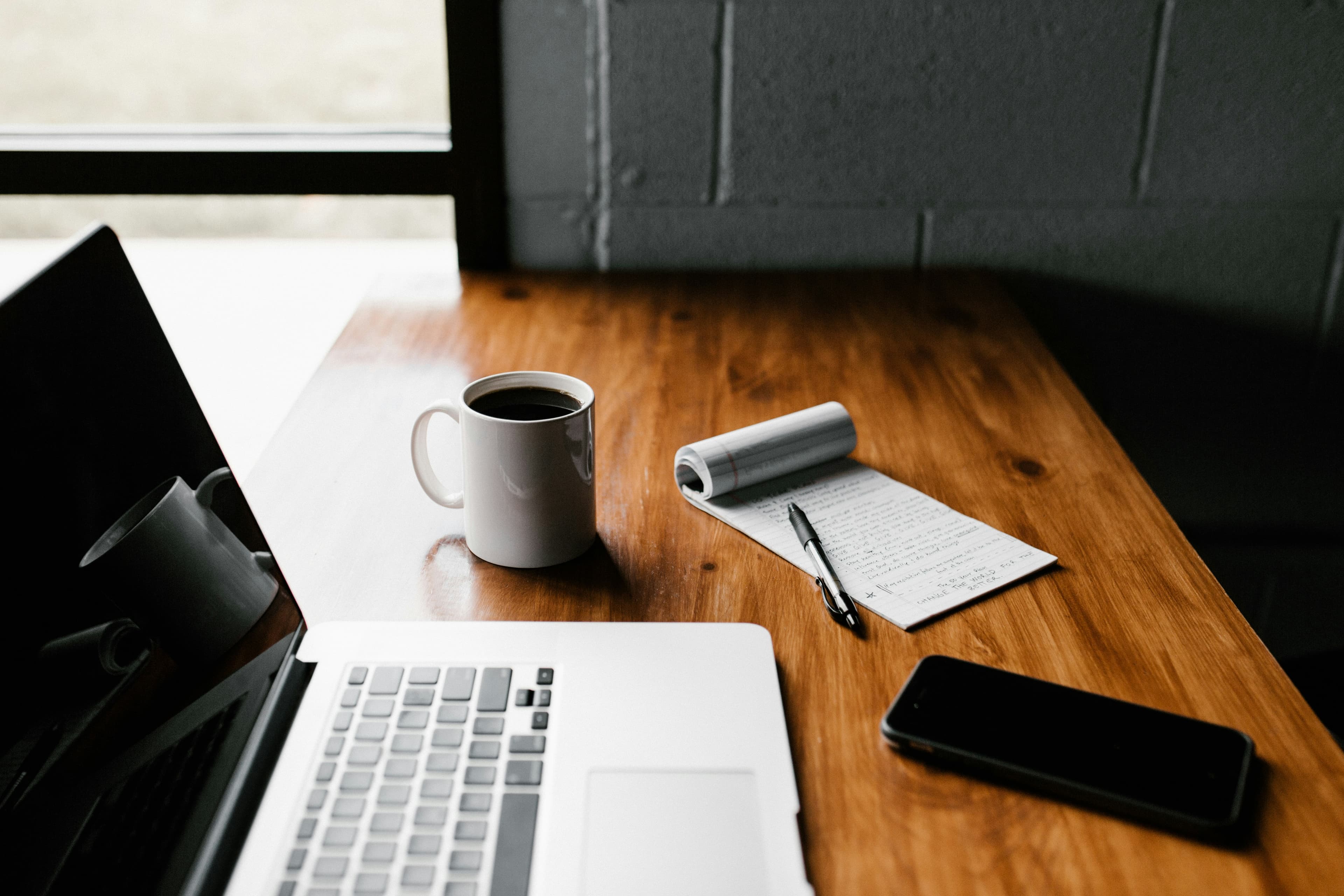 Laptop, mug and notebook on desk